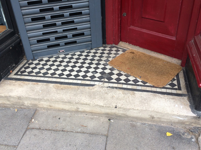 Figure 53: Surviving tiled entrance step at no.67 Sheen Lane. The shopfront has been subdivided